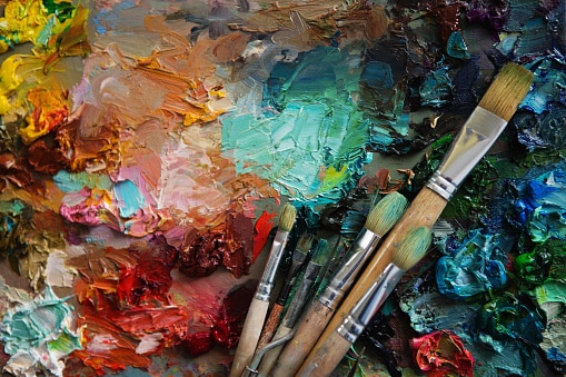 artists brushes and oil paints on wooden palette. Vintage stylized photo of paintbrushes closeup and artist palette. palette with paintbrush and palette-knife. Learn art online classes. 