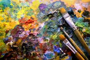 Palette with paintbrushes. Colorful palette with three paintbrushes. Why Artists are Drawn to Acrylic Painting - Yarnell School Online