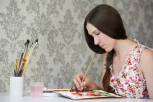 Young woman painter drawing watercolor poppies at her home studio. Tips for Painting with Watercolors - Yarnell School Online