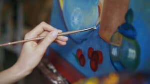 An acrylic painting in progress showing an artist adding shadows and highlights to a still life with vase, fruit and flowers. add-depth-and-dimension-in-acrylic-painting - Yarnell School of Fine Art