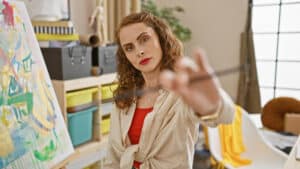 Young female artist absorbed in creativity, intently eyeing paintbrush - composition mistakes in painting - Yarnell School of Fine Art