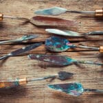 Artist palette knifes on old wooden rustic table. palette knife vs brush - Yarnell School of Fine Art